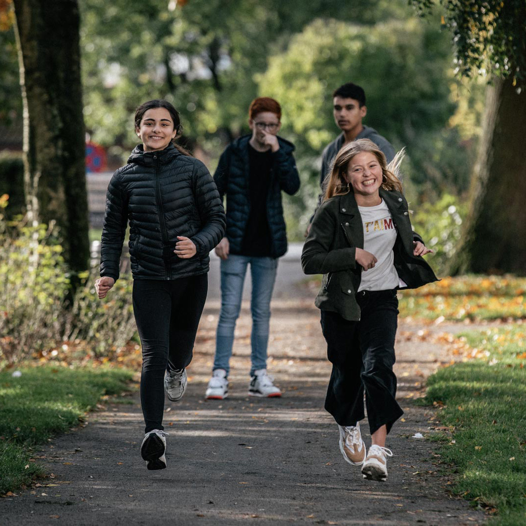 To piger kommer løbende, mens to drenge kigger på. FOTO: Jonas Normann (modelfoto)